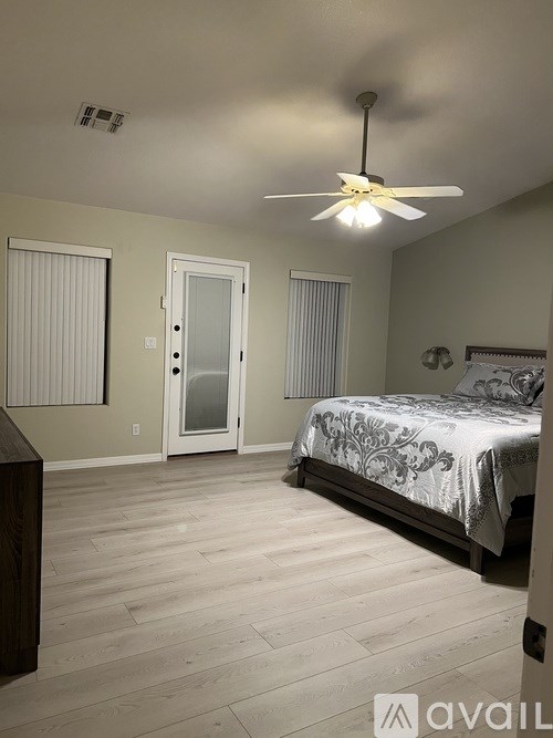 A bedroom with a bed, a ceiling fan, and a door.