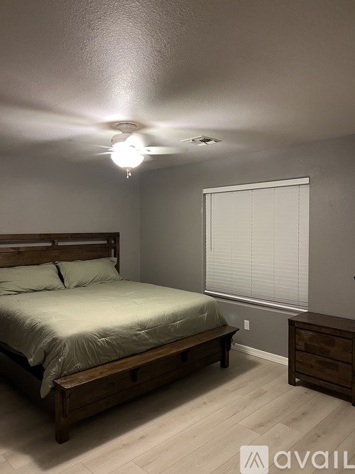 A bedroom with a bed, nightstand, and window.