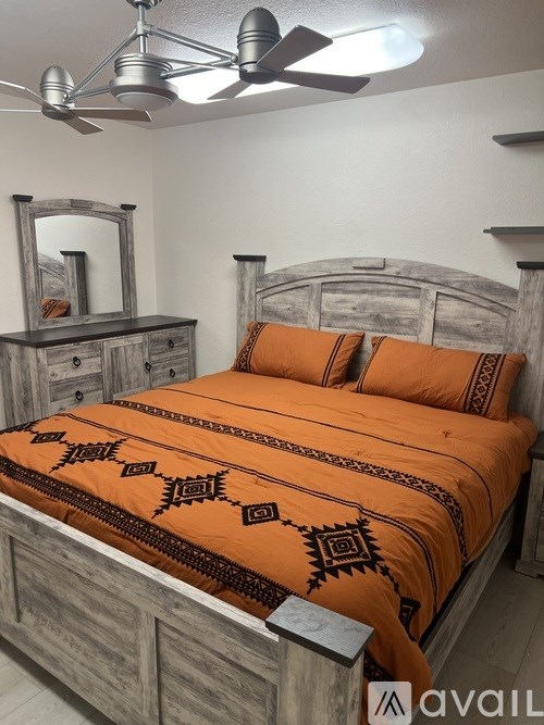 A bedroom with a bed, dresser, and mirror.