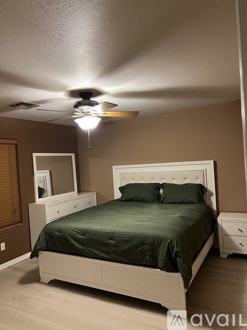 A bedroom with a bed, nightstand, and a ceiling fan.