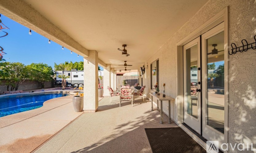 A patio with a table and chairs is shown with a pool in the background.
