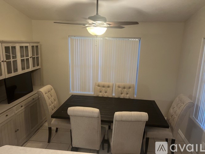 A dining room with a black table and white chairs.