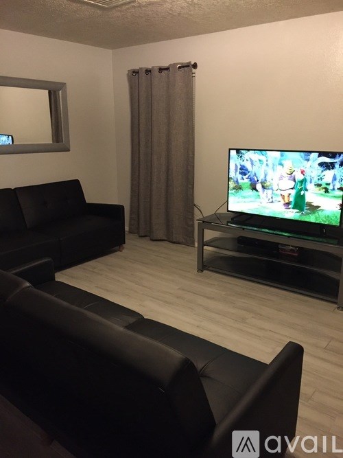 A black couch in a room with a television and a mirror.