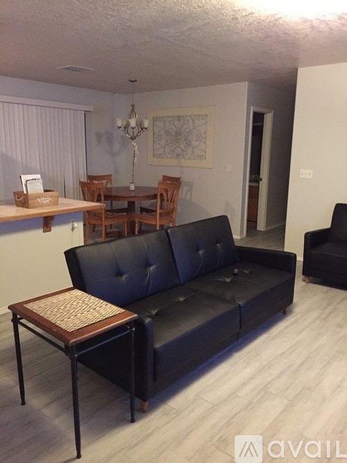 A living room with a black couch and a wooden coffee table.