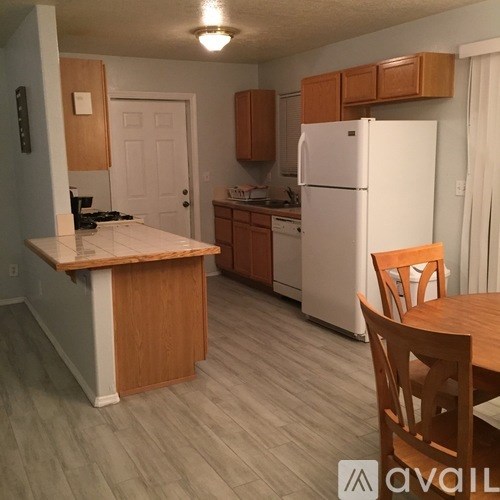 A kitchen with a white refrigerator, wooden cabinets, and a wooden table with chairs.