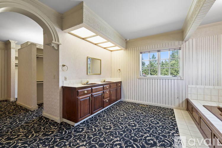 A room with a patterned carpet and a window overlooking trees.