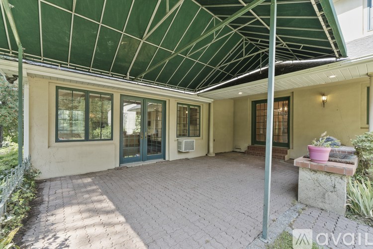 A covered patio area with a bench and potted plants.