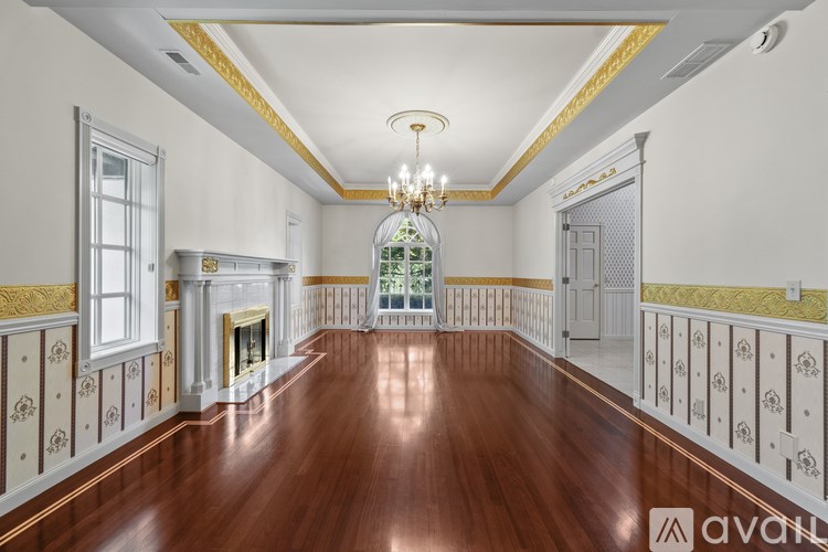 A large, empty room with wood floors and a chandelier.