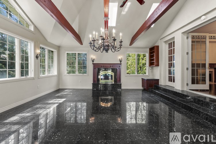 A spacious room with a black marble floor and a chandelier.