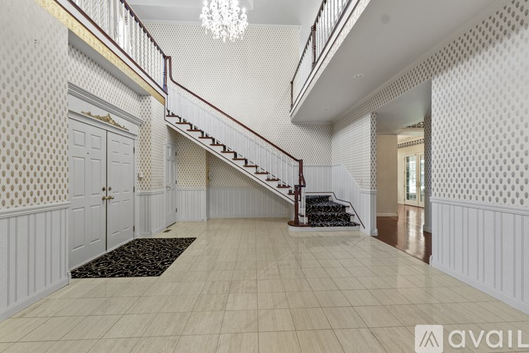 A spacious hallway with a staircase and patterned wallpaper.
