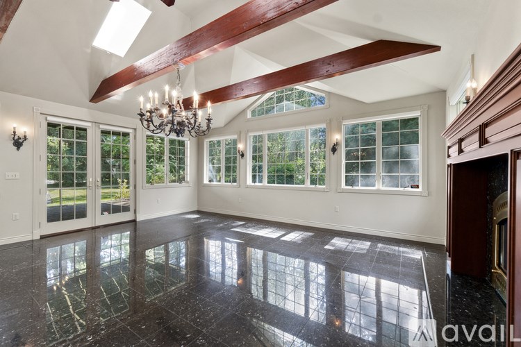 A spacious room with a chandelier, large windows, and a marble floor.