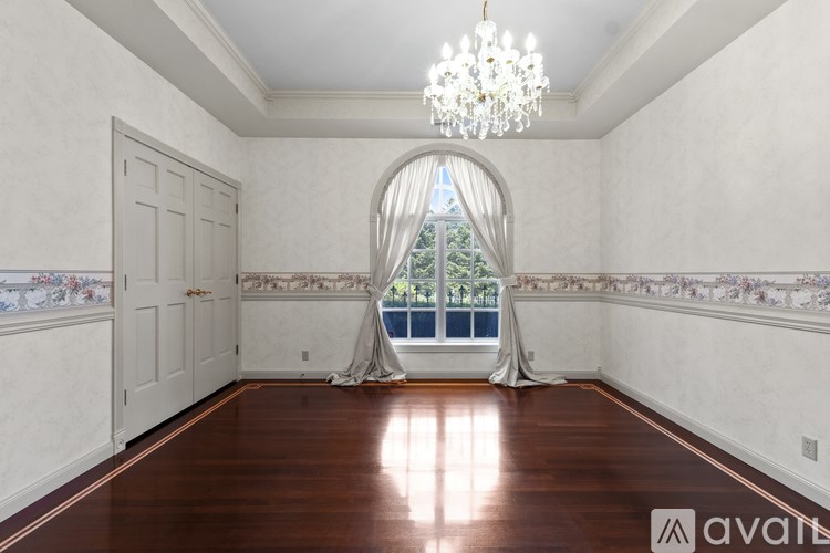 A large room with a chandelier and a view of trees through an arched window.