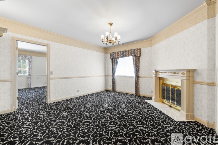 A large empty room with a chandelier and a fireplace.