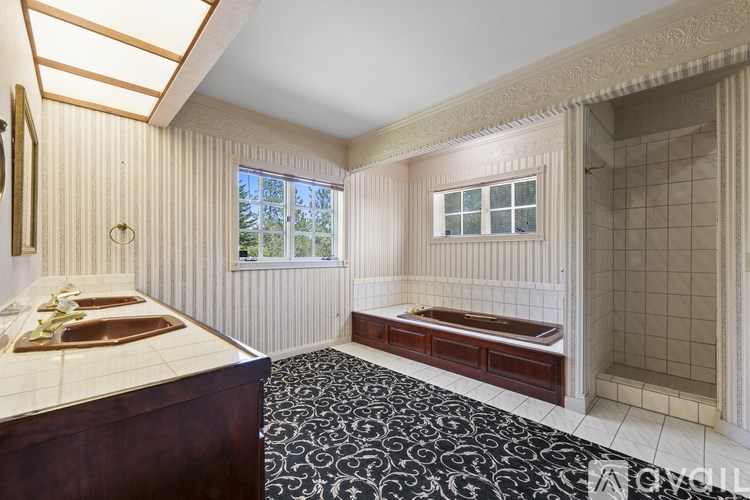 A bathroom with a black and white floor mat and a wooden vanity.