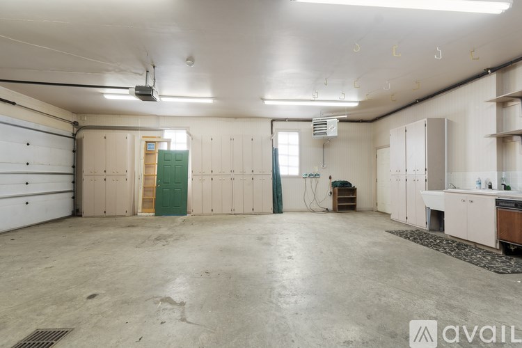 A large, empty garage with a green door and white walls.