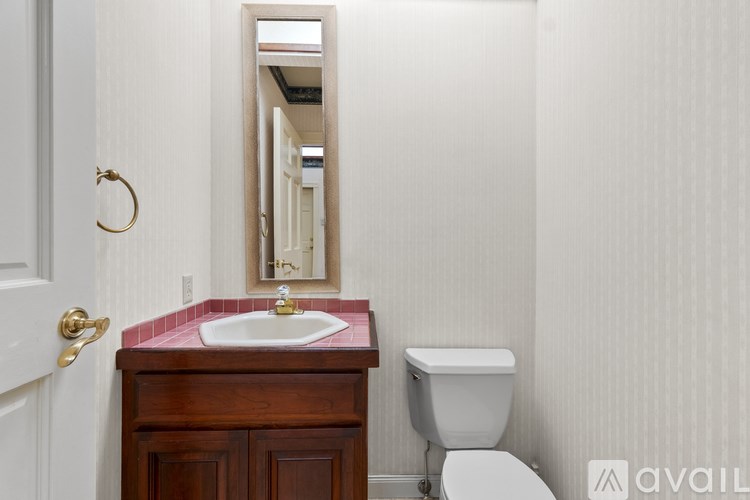 A bathroom with a sink, toilet and mirror.
