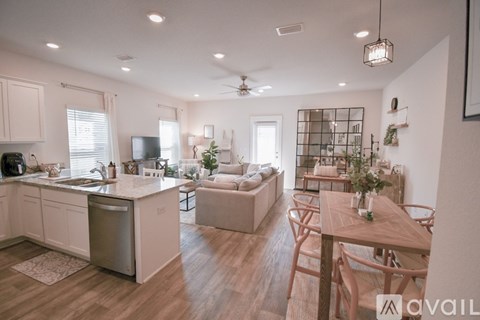 A well-lit, modern kitchen and living room with a dining table and chairs.