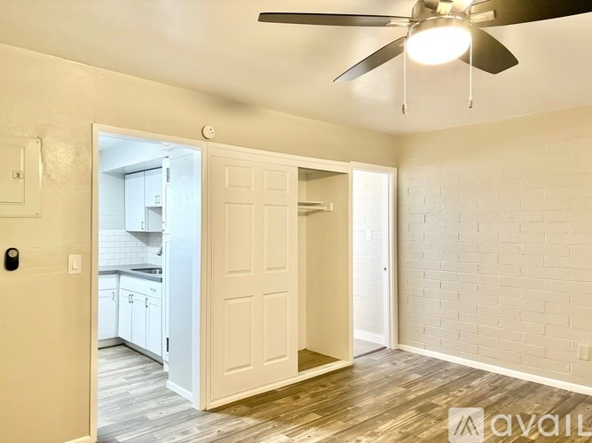 A room with a ceiling fan and a doorway leading to a kitchen.