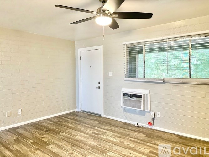 A room with a ceiling fan, a door, and a window with blinds.
