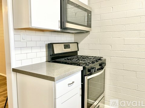 A kitchen with a black stove top oven and a microwave above it.