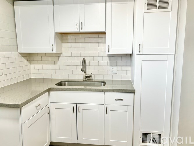 A kitchen with white cabinets and a stainless steel sink.