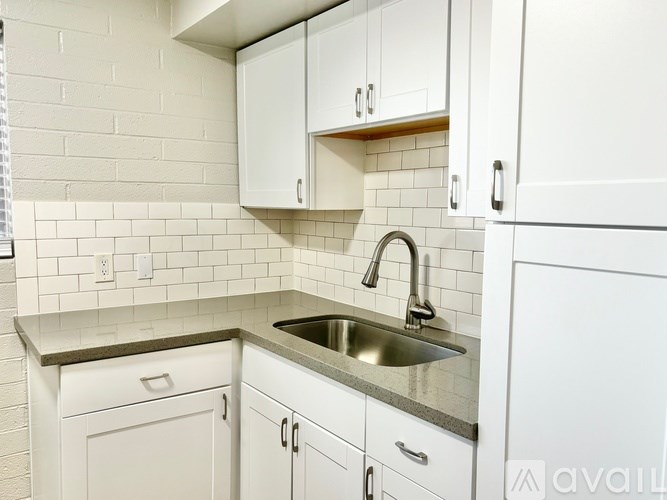 A kitchen with white cabinets and a stainless steel sink.