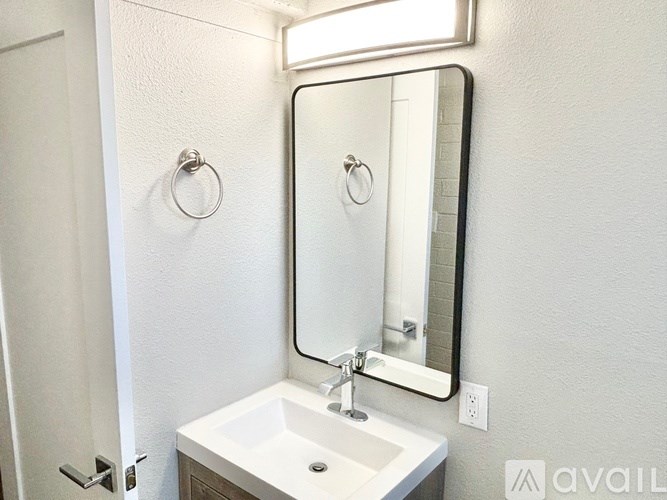 A bathroom with a sink, mirror, and towel ring.