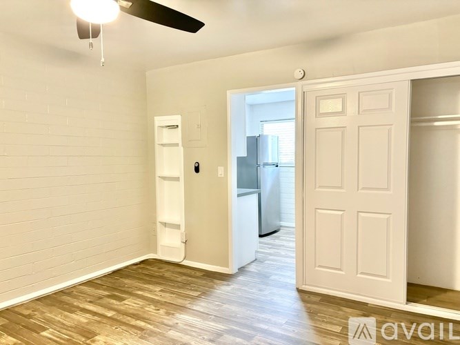 A white refrigerator is in a kitchen with wood flooring.