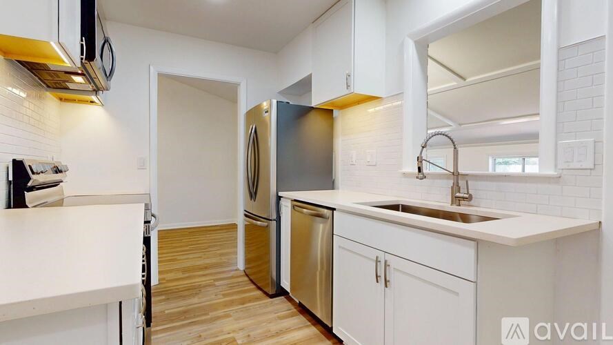 A kitchen with white cabinets and a wooden floor.