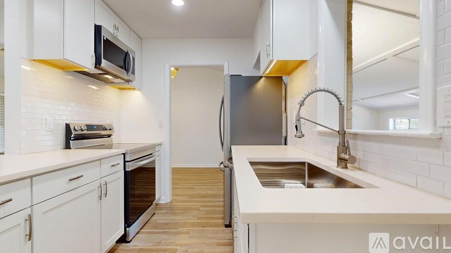 A kitchen with white cabinets and a wooden floor.