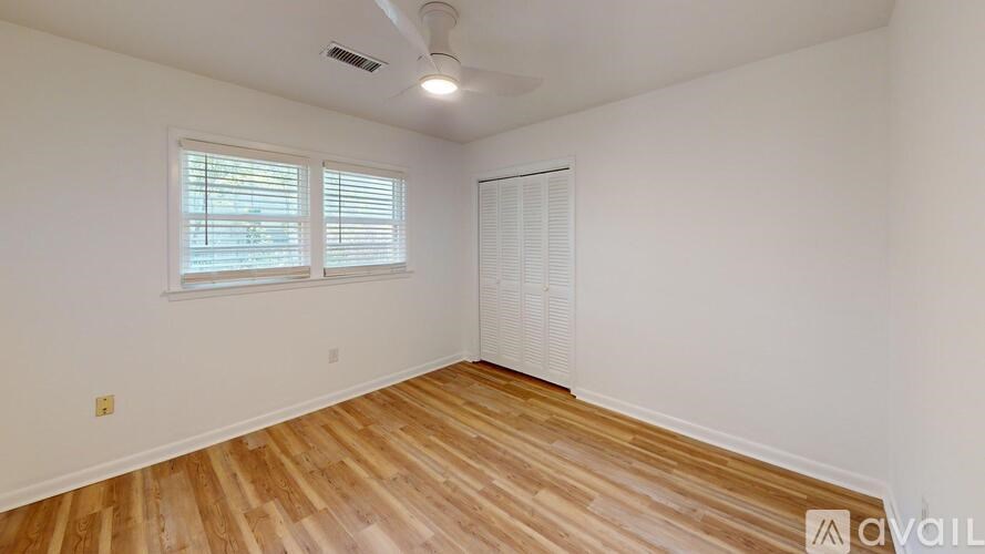 A room with wooden flooring and a window with blinds.