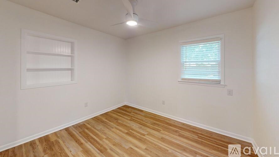A room with wooden flooring and a window with blinds.
