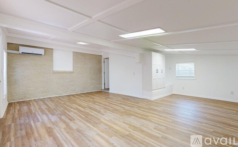 A spacious room with wooden flooring and a window.
