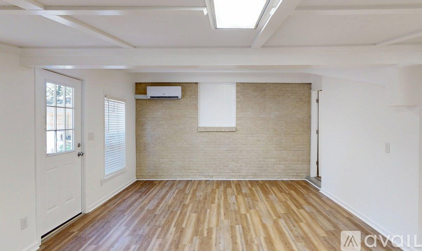 A room with wooden flooring and a window with blinds.