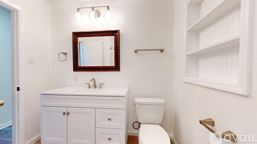 A white bathroom with a toilet, sink, and mirror.