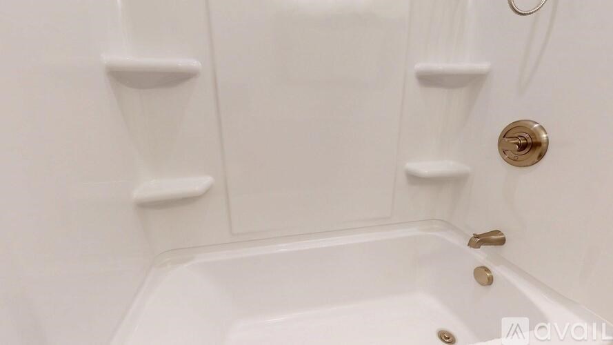 A white bathtub with a gold faucet and a white shower head.