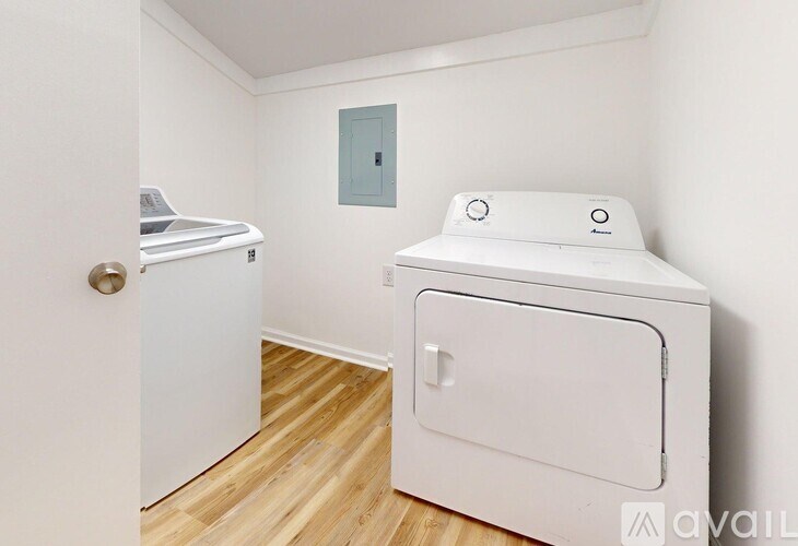 A white dryer is sitting in a small room with a door and a window.