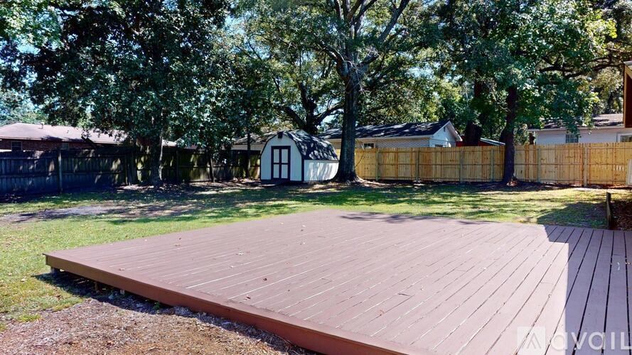 A backyard with a wooden deck and a tree.