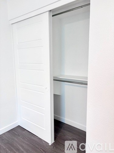 A white door is open to a room with a wooden floor.