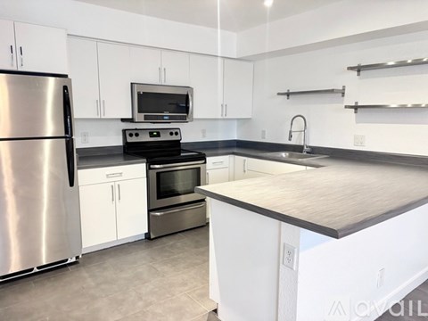 A kitchen with white cabinets and a stainless steel refrigerator.