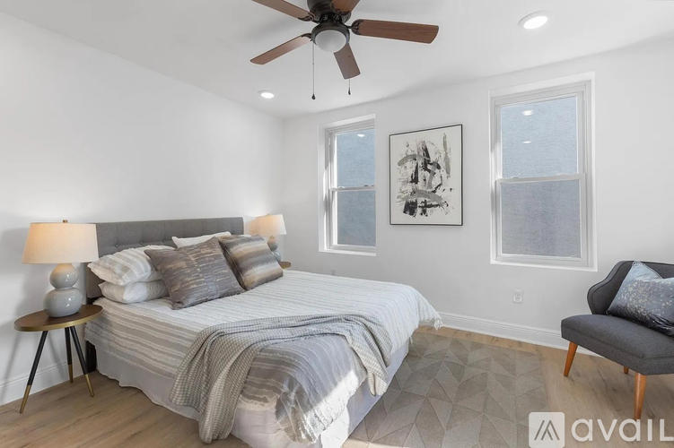 A bedroom with a bed, a ceiling fan, and a chair.