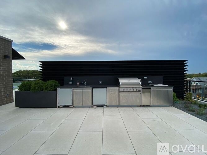 A modern outdoor kitchen setup with a grill, sink, and refrigerator.
