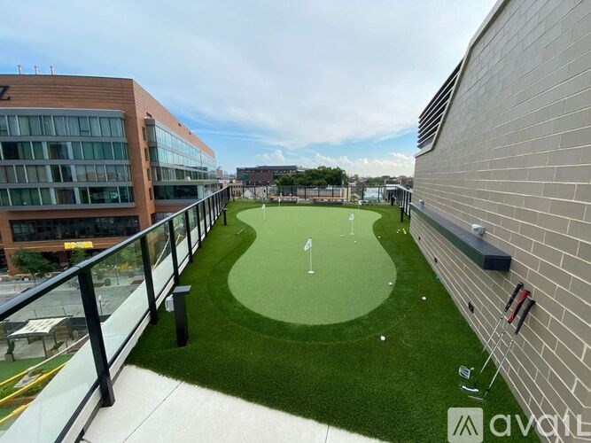 A small putting green is surrounded by a brick wall and a metal railing.
