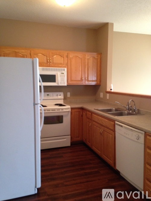 A kitchen with white appliances and wooden cabinets.