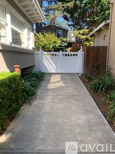 A white fence and gate in front of a house.