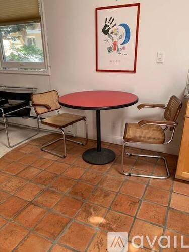 A round table with a red top and four chairs with a tiled floor.
