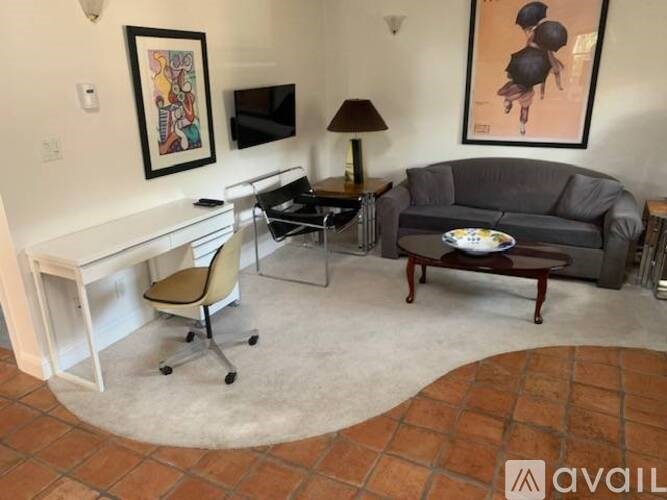 A living room with a grey couch, a white desk, and a chair.