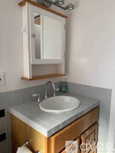 A bathroom with a white sink and a wooden cabinet.