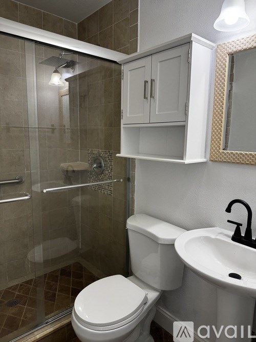 A bathroom with a toilet, sink, and shower.