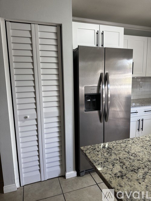 A stainless steel refrigerator with a water and ice dispenser in the middle of the door stands in a kitchen.